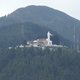 Fotografía del cerro de Guadalupe. Muestra un edificio blanco en la cima de una montaña con una estatua de la virgen, rodeado de un paisaje natural impresionante y cielo despejado.