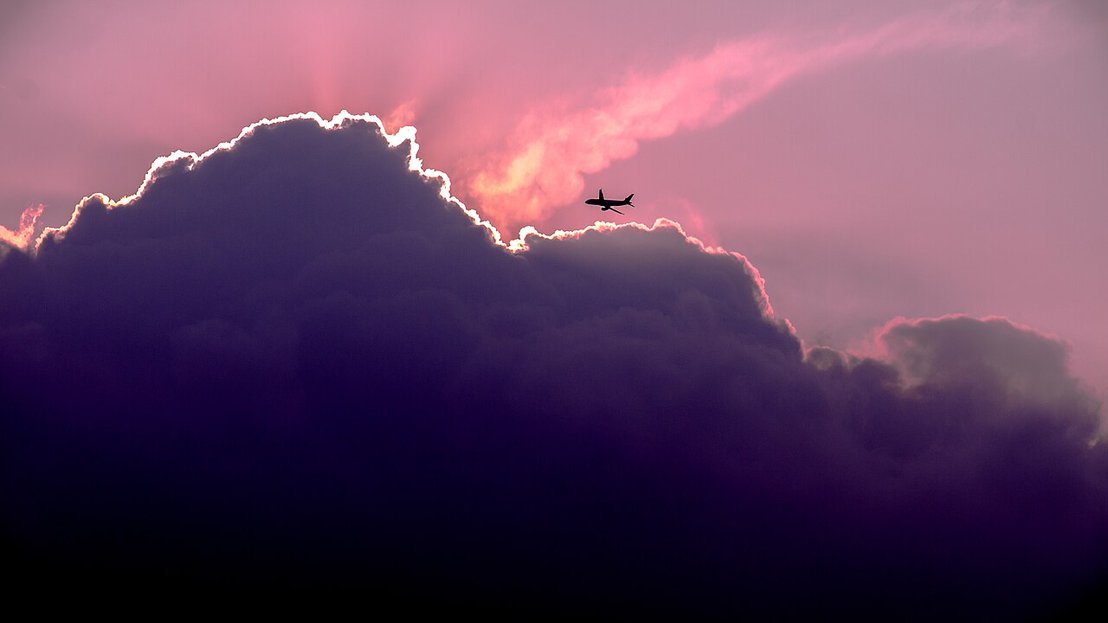 Cielo de Bogotá con una nube  y un avión pequeño con tonalidades rosa y blanco
