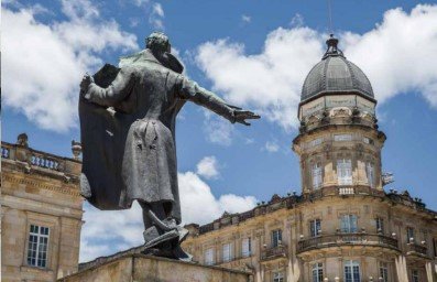Escultura en el centro de la ciudad desde una perspectiva en la que señala al colegio San Bartolomé